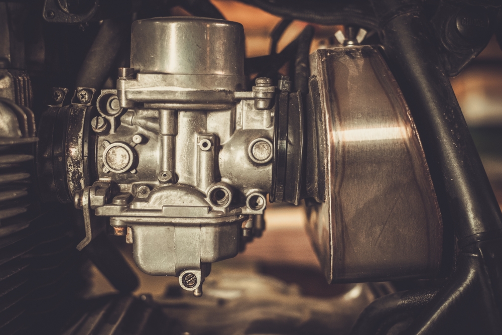 A close up of a carburettor motorcycle engine.